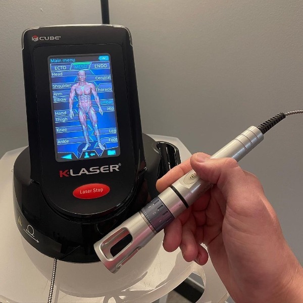 K-Laser therapy device with handheld applicator used for targeted pain and tissue treatment.