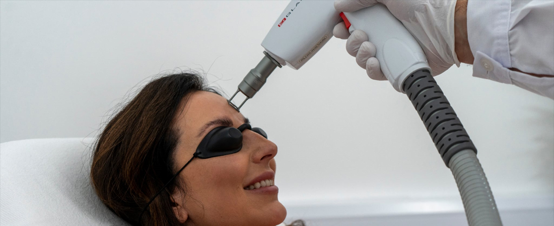 Woman with eye shields receiving laser treatment on her forehead.